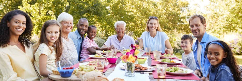 A diverse multi-generational family gathered around an outdoor table